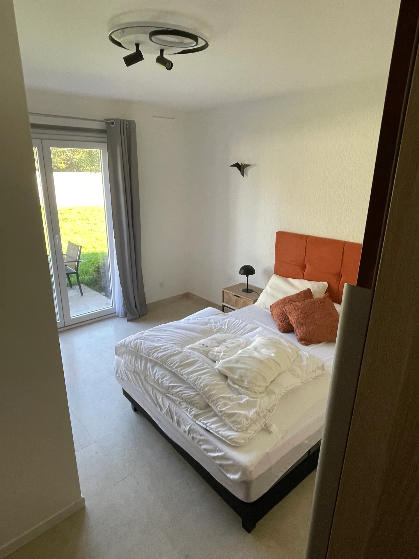 Chambre 2 de La Villa, au rez-de-chaussée : lit double, tête de lit rouille et porte-fenêtre sur le jardin